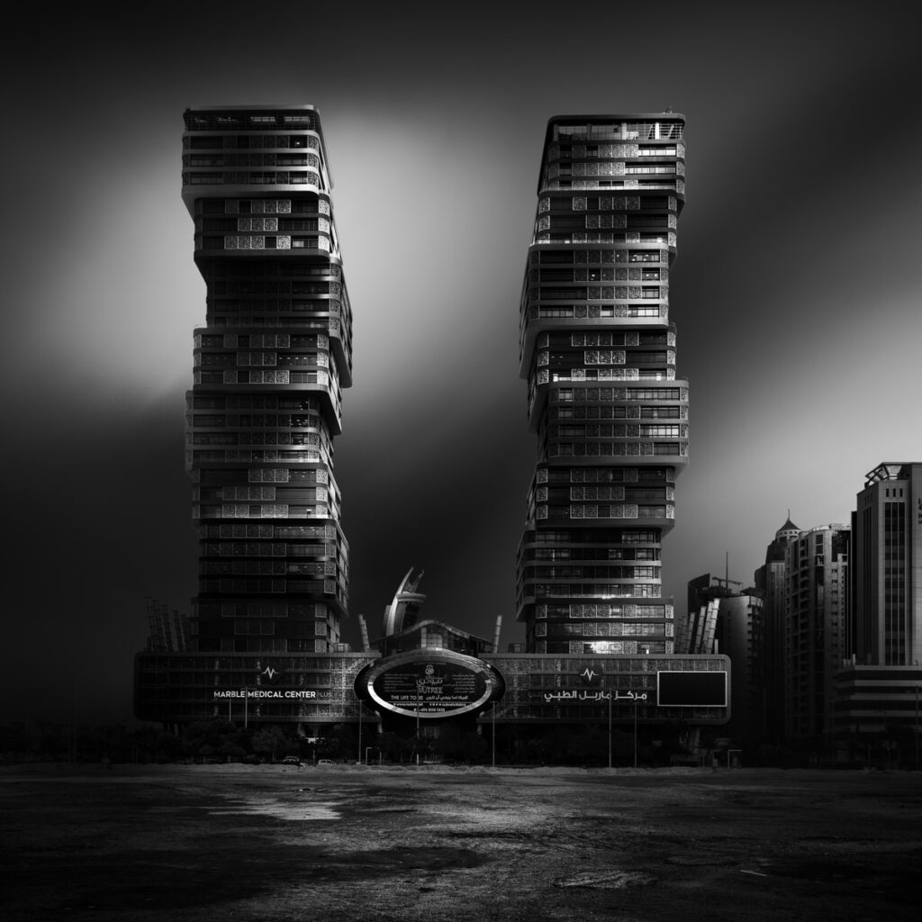 black and white photo of two towers with buildings in the background