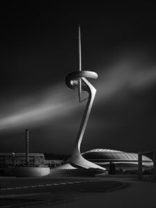 communication tower in fron to a stadium on a cloudy day