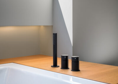 modern-bathtub-with-black-fittings-and-wood-paneling-under-natural-light