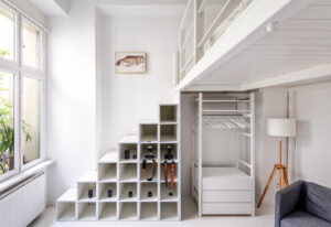 Minimalist loft bedroom with shelving system and large window front - Architekturfotografie Berlin & Hamburg