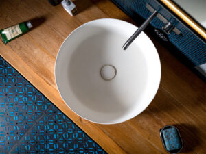 Modern architectural photography of a round countertop washbasin on a wooden panel in a designer bathroom in Hamburg - detail shot from above