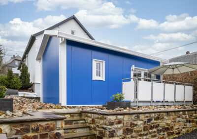 Blaues Tiny House mit Terrasse und Steinmauer und Treppe