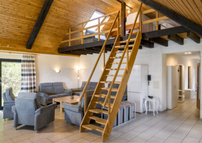 Wohnzimmer mit steiler Treppe in einer Maisonettewohnung im Dachstuhl eines Hauses