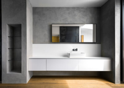 Modernes Badezimmer mit Betonwand und einem weissen Waschbecken und holzfussboden