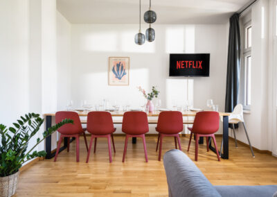 Wohnzimmer einer Ferienwohnung mit großem Esstisch, auf den das Sonnenlicht strahlt