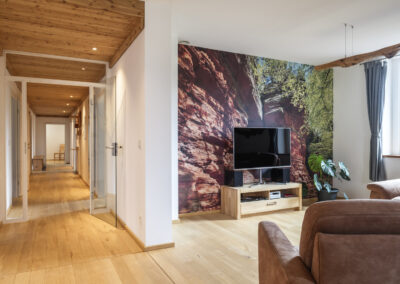 Langer Flur und anschließendes Wohnzimmer mit Holzdecke und Parkettboden