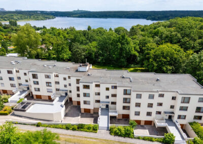 Luftaufnahme eines modernen Wohnbaufeldes in Berlin direkt an einem See und Waldgebiet, professionell fotografiert mit einer Drohne für die Immobilienvermarktung.