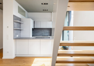 Innenansicht einer kleinen Wohnung mit moderner Küche und Treppe, die eine effiziente Raumnutzung veranschaulicht.